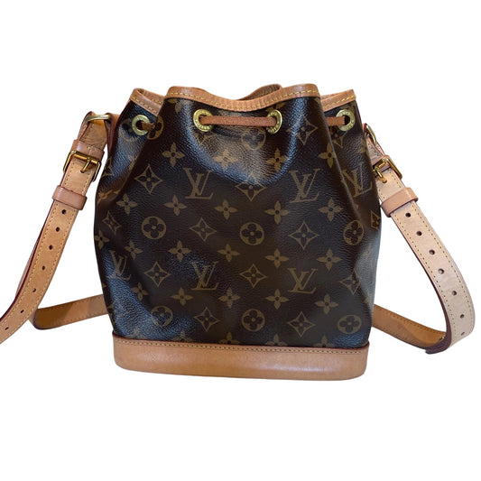 Louis Vuitton Petit Noe bucket bag in classic brown Monogram canvas. Features a solid tan Vachetta leather base, leather drawstring closure, and adjustable shoulder strap. Front view.
